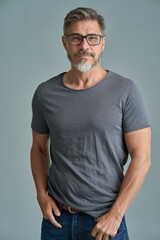 Portrait of happy casual older bearded man with glasses and gray hair smiling, Mid adult, mature age guy standing, isolated on gray background.