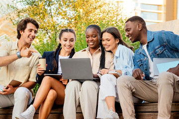 Diverse students friends sitting on bench outdoors in university campus