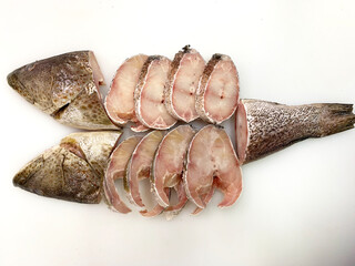 fresh raw cold seafood grouper fillet cut grey whole fish ikan on white ice background halal food...