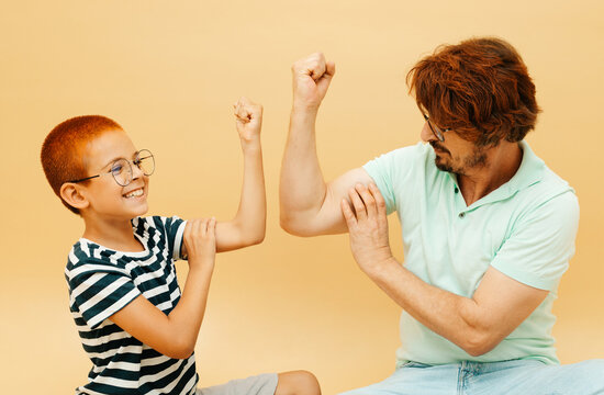 Happy child and his father playing together. Father and son compete in arm wrestling
