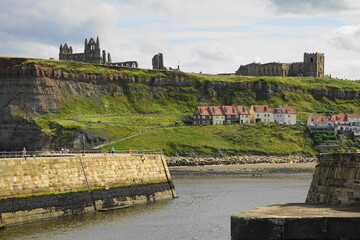 Whitby – with the 13 century Abbey  and the Church of Saint Mary on the cliff overlooking the town,  North Yorkshire, England - famously linked by Bram Stoker's novel Dracula. - obrazy, fototapety, plakaty