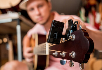 Young musician tuning a classical guitar in a guitar shop