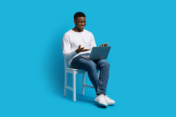 Black guy sitting on chair, have video call on laptop