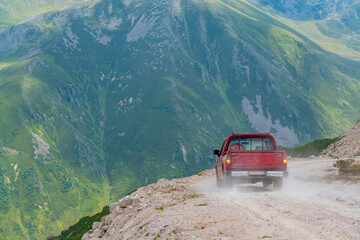 A red pickup truck driving on dirt roads on high plateau roads