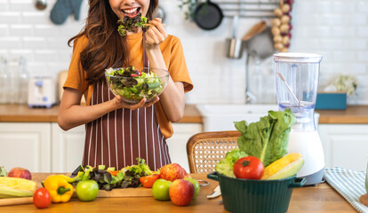 Portrait of beauty body slim healthy asian woman eating vegan food healthy with fresh vegetable salad in kitchen at home.diet, vegetarian, fruit, wellness, health, green food.Fitness and healthy food