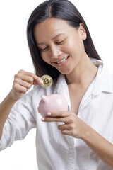 Asian American Woman saving Bitcoin into a piggy bank