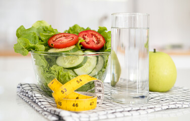 diet, healthy eating, food and weigh loss concept - close up of Fresh fruit ,water and measuring tape with salad on white table in kitchen