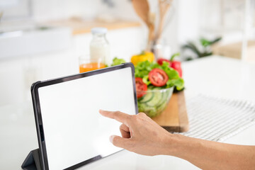 Female hands pointing tablet blank screen, searching healthy menu recipe on the internet over her...