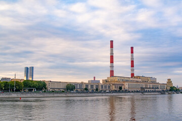 Fototapeta na wymiar Moscow, Russia - August 12, 2022 : Thermal power plant in Moscow on the waterfront and a motor ship taking a boat trip