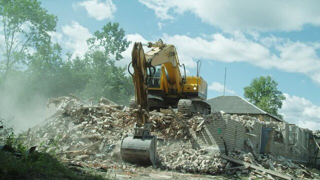 excavator destroys or demolishes a brick building, heavy machinery at work