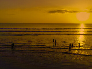 The twilight atmosphere at Legian Beach, Bali. Silhouettes of people enjoying the sunset while playing on the beach.