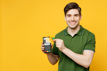 Young happy man he wears green t-shirt casual clothes hold wireless modern bank payment terminal to...
