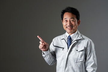 左側を指差すミドルエイジの作業員　黒背景