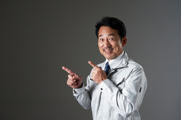 左側を指差すミドルエイジの作業員　黒背景
