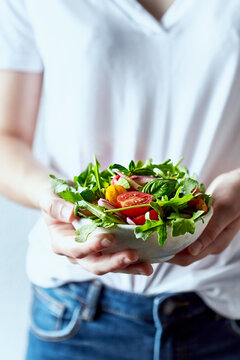 Young woman holding a bowl of healthy arugula and cherry tomato salad. Healthy lifestyle concept