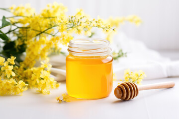 Jar of honey, mimosa and honey spindle on a light background with copyspace.