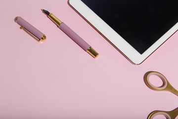 cute planner with golden elements, glasses, pen, laundry, stapler and tablet on a pink background. ...