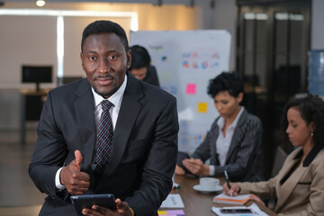 Portrait of  black African businessman posing thump up in meeting room with his team