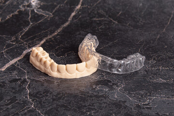 Aligners for teeth alignment and plastic jaw model. Black background. Polycarbonate mouth guard
