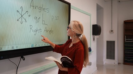 Closeup of happy female teacher writing on an interactive whiteboard teaching geometry math in a...