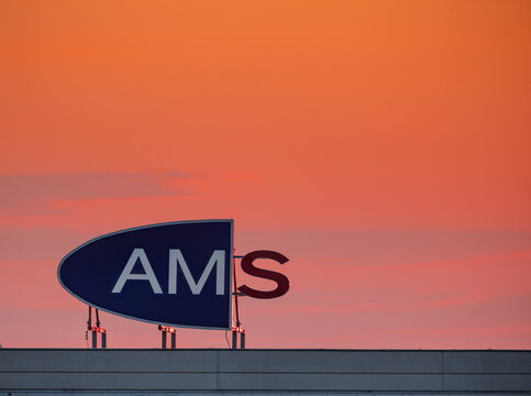 Vienna, Austria: AMS the Austrian unemployment agency sign against orange sky at sunrise
