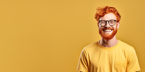 Attractive ginger man wearing yellow tshirt and glasses. Isolated on yellow background. 