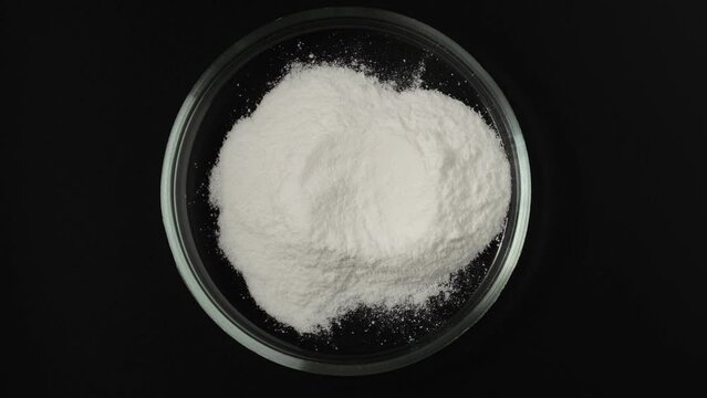 Food additive E363.  Succinic acid in Petri dish, top view. Dicarboxylic acid. Spirit of amber, white powder. Flavoring agent, contributing a somewhat sour and astringent component to umami taste.