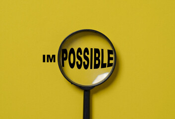 Magnifier glass focusing to possible from impossible wording on yellow background , Positive...