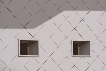 2 air vents on aluminum composite tile wall of modern industrial building with sunlight and shadow on surface in monochrome style