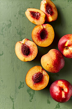 Whole and halved nectarines on rustic painted background. Top view. Copy space