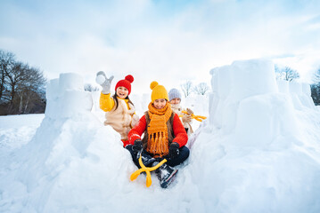 Group of children make snowballs for snowball fights. Children play in snow fort made of ice...