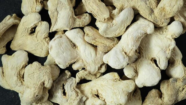 Dried ginger root on dark background. Ginger is ground and used as spice in cooking and folk medicine. 4K video, Rotating.