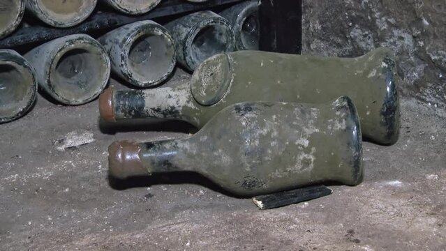 Old Aged Wine Bottles Storage in Dark Rustic Cellar Basement, Stack of Lying Dir