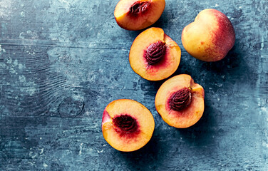 Whole and halved nectarines on rustic painted background. Top view. Copy space