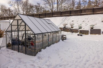 Gorgeous winter view of small garden and greenhouse with collected things for winter. Gardening concept. Sweden.