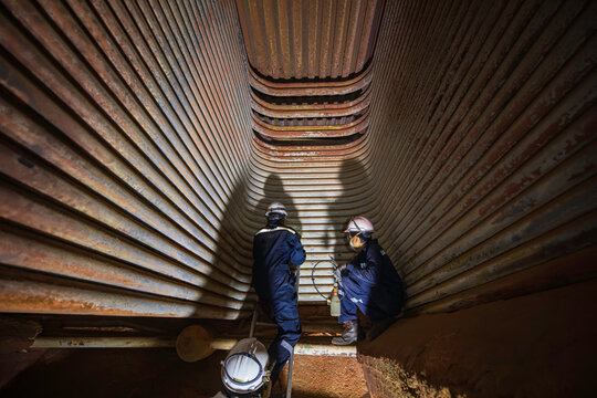 Engineer in inspection and repair of coil heater gas equipment of boiler room. Steel structure cleaning and maintenance of industrial steam boilers in dangerous confined