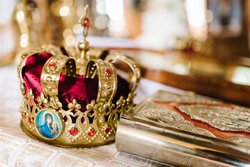 Wedding crown stand on the table in church. Holy Bible decorated with gold icons. Wedding ceremony. Closeup. Divine Liturgy.