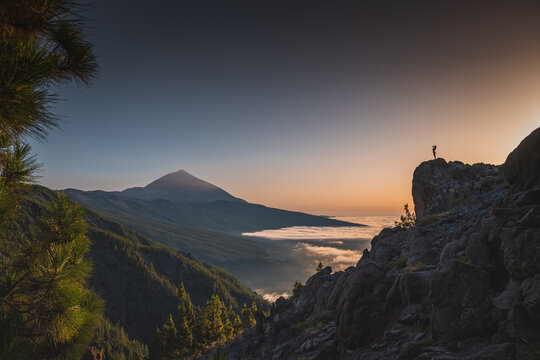 Girl silhouette on a rock in a distance above the clouds in front of Teide volcano