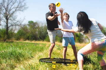 family playing spikeball in nature. parents with children play active games on summer holidays. Spikeball is a miniature analogue of volleyball.