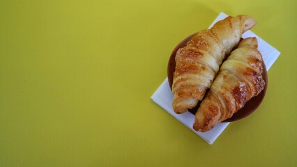pile of Fresh mini Croissant on white plate. isolated on yellow background.