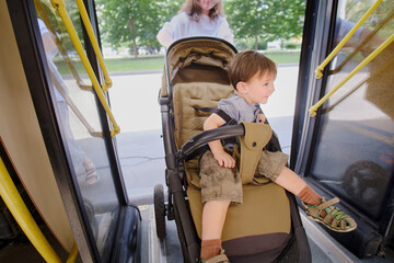 The child is getting on the bus with their mom, ready to board and find a seat. Kid boy aged two years (two-year-old) © Андрей Журавлев