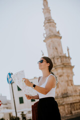 Female tourist with city map by the Saint Oronzo statue in Ostuni, Italy
