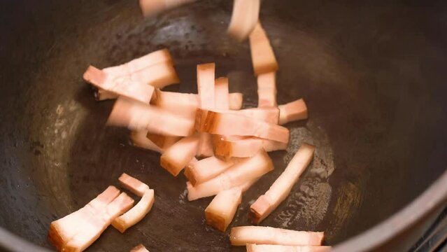 roasting of salted pork fatback on a red-hot pan, close-up