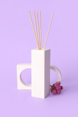 Floral reed diffuser and flowers on purple background