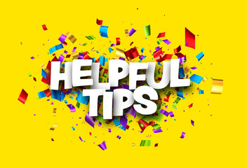 Helpful tips sign with colorful cut out foil ribbon confetti on yellow background.