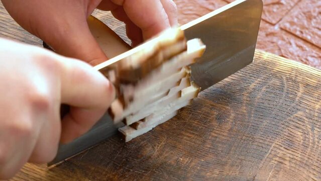 Slicing of salted pork fatback on cutting board, close-up	
