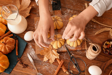 Woman preparing pumpkin shaped buns on wooden background - obrazy, fototapety, plakaty