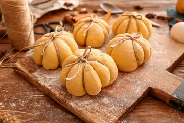 Board with pumpkin shaped buns on wooden background