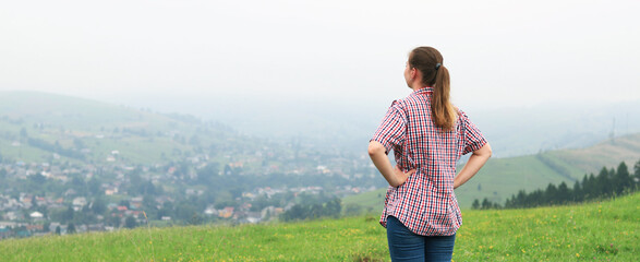 Relaxed girl breathes fresh air in the mountains. The concept of relaxation, outdoor living and recreation. A trip to the Carpathian mountains, Ukraine. View from the back of a girl in nature