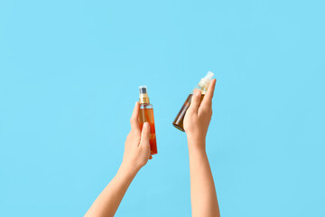 Woman with cosmetic spray bottles on blue background